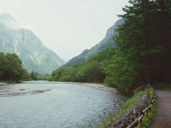 Scenic view of river by mountains against sky