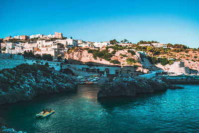 Buildings by sea against clear blue sky