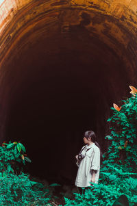 Young woman looking away while standing at cave