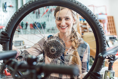 Portrait of smiling woman holding bicycle wheel