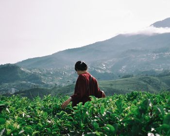 Rear view of a woman looking at mountains against sky