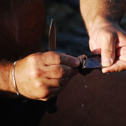 Close-up of man hands holding mussel and knife
