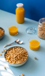 Breakfast concept with cold cereals and orange juice on blue background