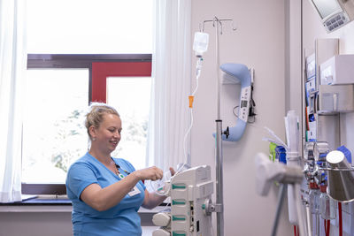 Female doctor using medical equipment while standing in hospital