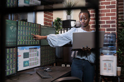 Young woman using laptop standing in office