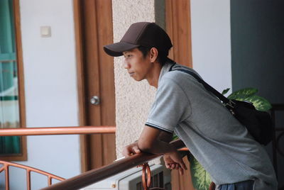 Side view of young man looking away while standing on railing