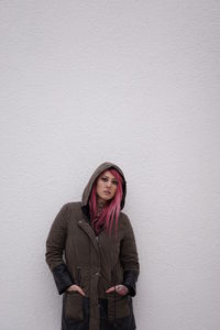 Portrait of woman standing against white wall