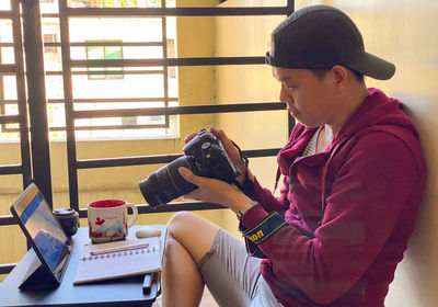 Man with camera using digital tablet while working at home