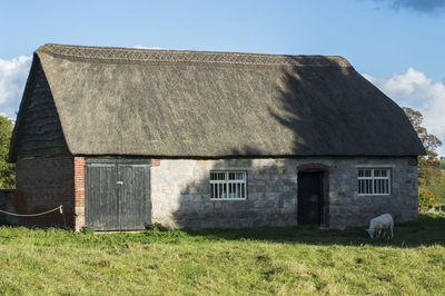 Exterior of old house on field against sky