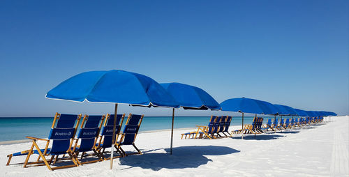 Blue beach chairs and umbrellas on beach seaside on vacation. 