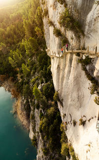 Travelers walking on lumber path on cliff in mont rebei canyon on summer day in pyrenees