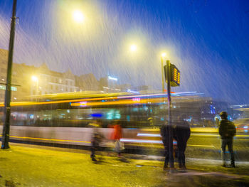 Blurred motion of people walking on road at night