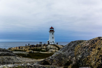 Lighthouse by sea against sky