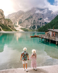 Rear view of women standing by lake against mountains
