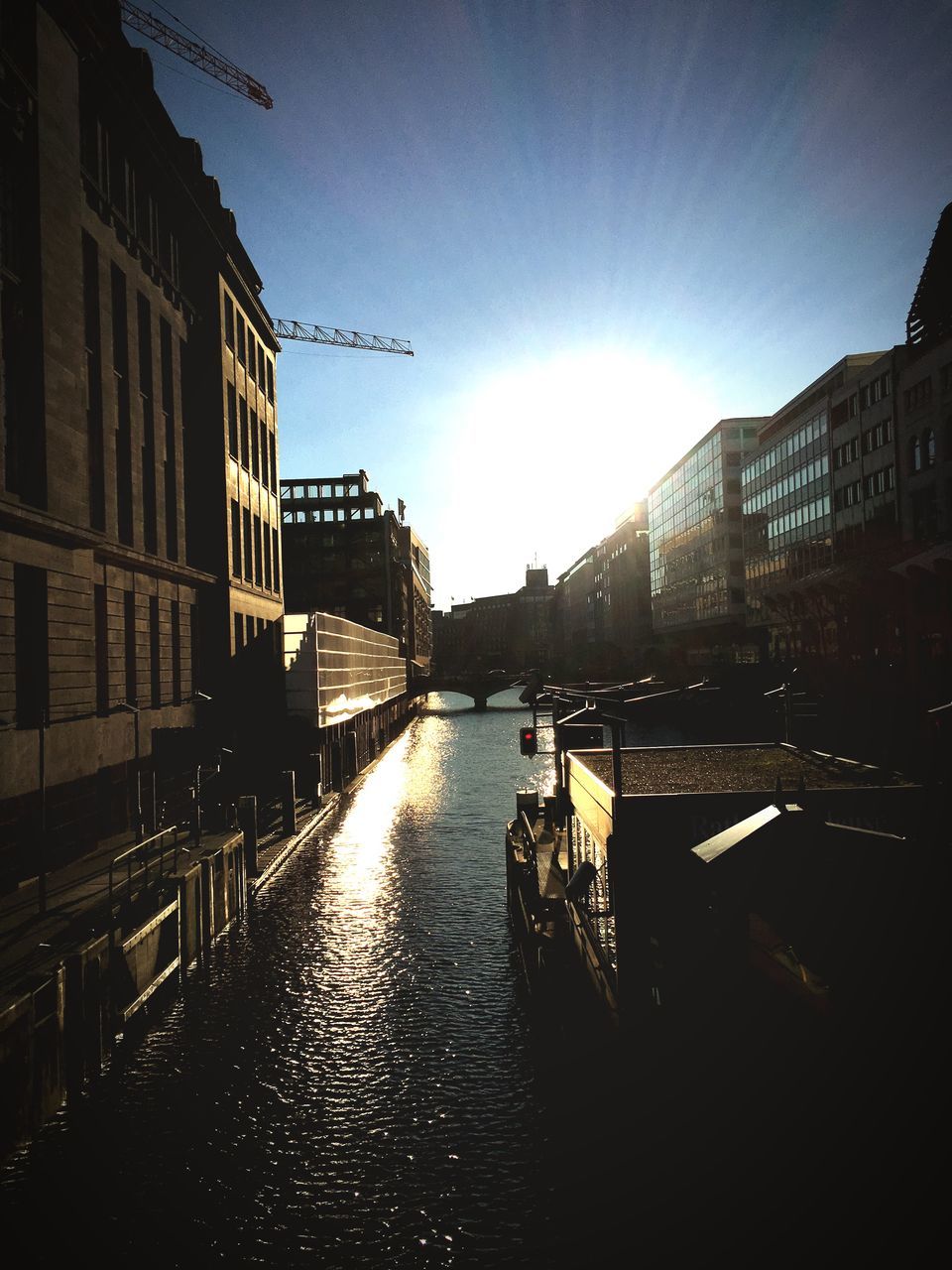 architecture, building exterior, built structure, water, canal, transportation, city, waterfront, mode of transport, nautical vessel, river, clear sky, building, reflection, sky, sunlight, residential structure, residential building, connection, bridge - man made structure