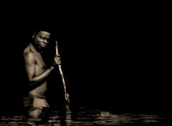 Young man standing against black background