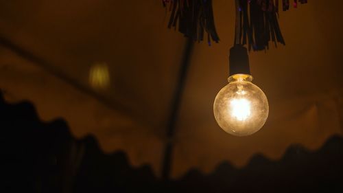 Low angle view of illuminated light bulb hanging