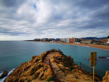 Scenic view of sea by city buildings against sky