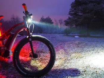 Bicycle by trees against sky at night