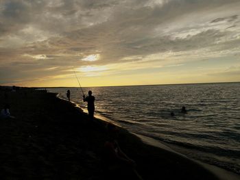 Silhouette man on beach against sky during sunset