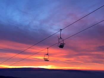 Low angle view of silhouette electricity pylon against sky during sunset