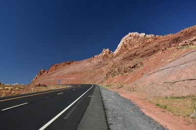 Road amidst mountains against clear blue sky