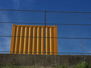 Close-up of chainlink fence against blue sky