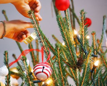 Cropped hands decorating christmas tree