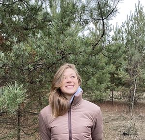 Portrait of a smiling young woman against trees