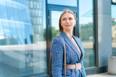 Portrait business woman smiling outdoors in business clothes against backdrop