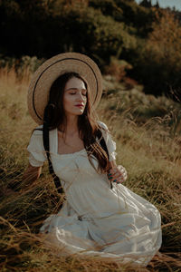 Young woman wearing hat sitting outdoors