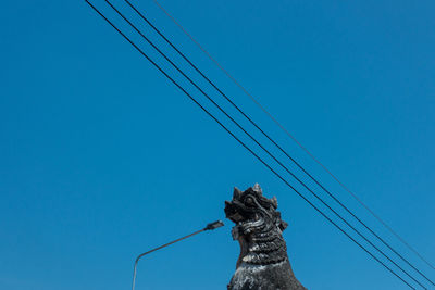 Low angle view of horse sculpture against clear blue sky