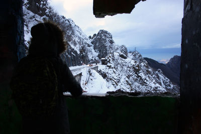 Rear view of man standing on snowcapped mountain