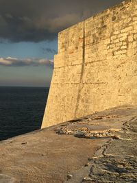 Stone wall by sea against sky