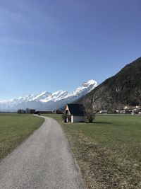 Road amidst field against sky