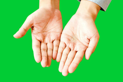 Close-up of hand holding hands over blue background