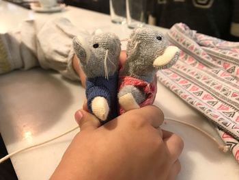 Cropped hands of girl holding toy animals at table