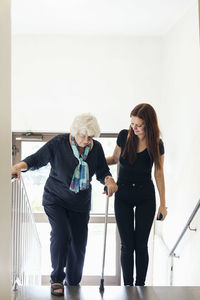 Young woman helping grandmother to climb steps