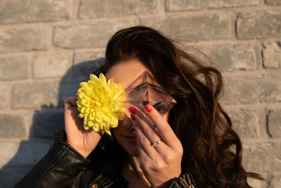 Portrait of woman with hand holding hair against wall