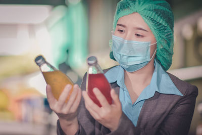 Close-up of woman wearing mask inspecting drinks in factory