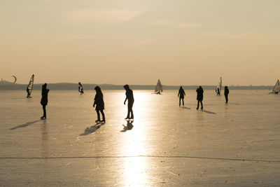 Silhouette people skating on ice rink during sunset