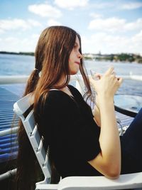 Beautiful woman sitting on boat at sea against sky