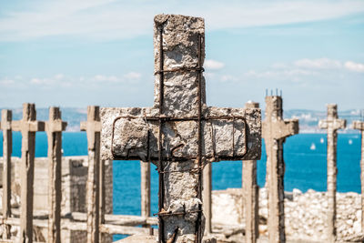 Close-up of old wooden post by sea against sky