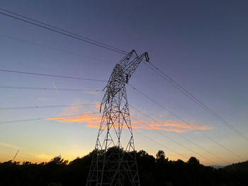 Low angle view of electricity pylon against sky during sunset