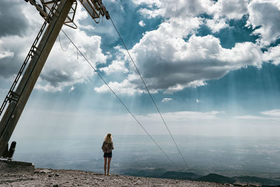 Rear view of woman standing on mountain against sky