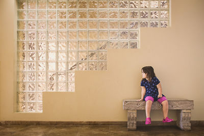 Full length of girl sitting against wall