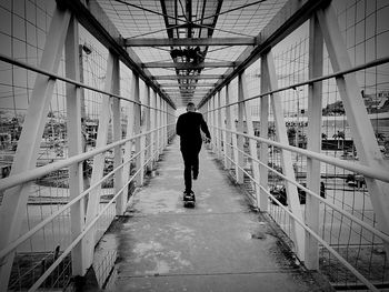 Rear view of man skateboarding on footbridge