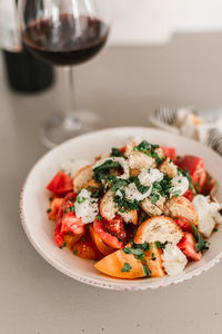 Italian pancanella salad in deep plate. fresh heirloom tomatoes. red wine in glass.