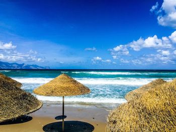 Deck chairs on beach by sea against blue sky