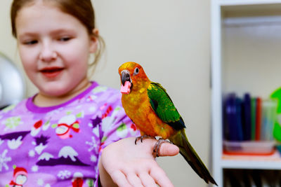 Girl holding bird at home